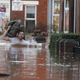 A local resident carries a bag as he wades through flood water on a residential street in Carlisle, Britain December 6, 2015. British police have declared a major incident in northern England after prolonged heavy rain caused widespread flooding and forced emergency services to evacuate residents from their homes. REUTERS/Phil Noble